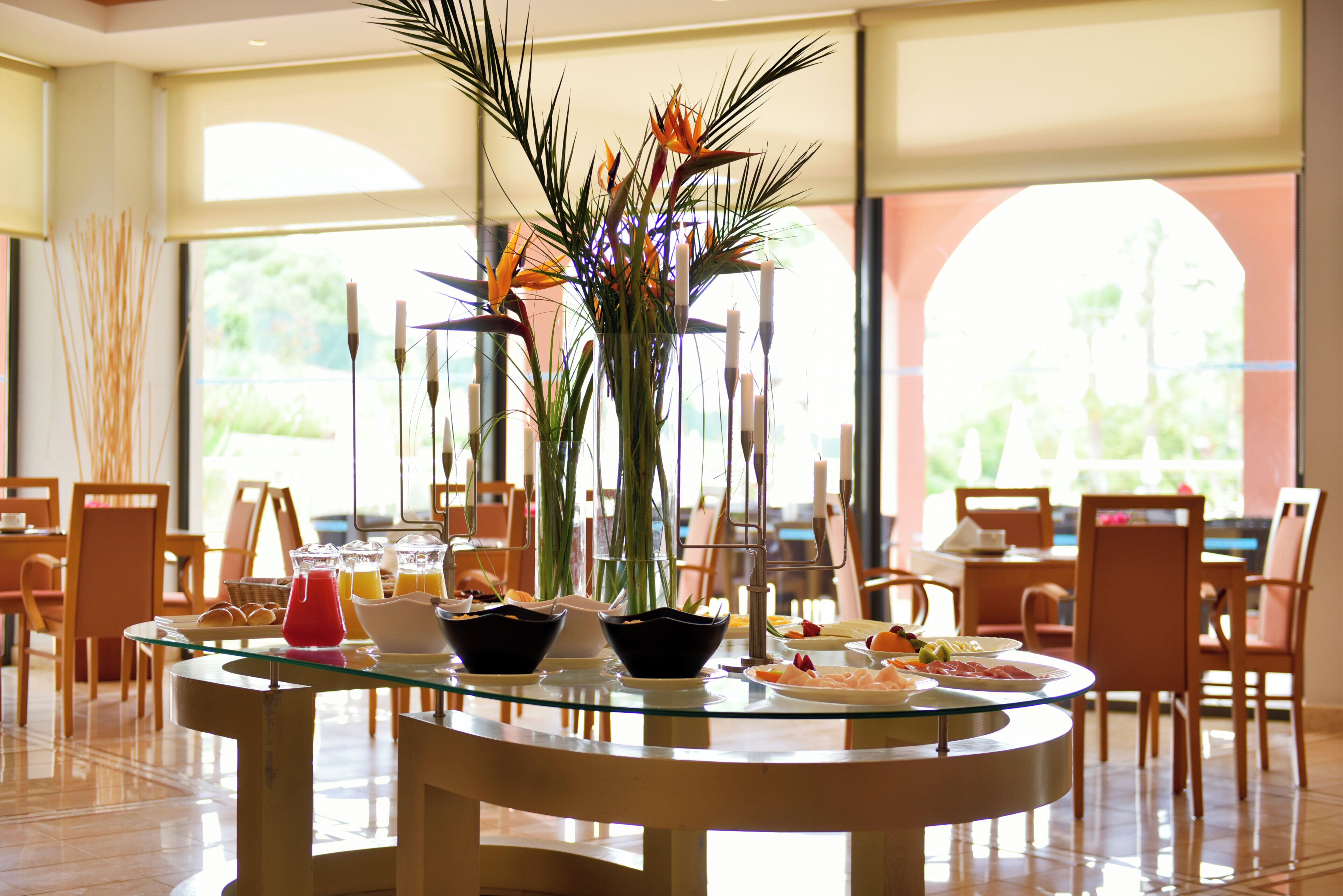 Un coin repas avec une table en verre, des chaises et un vase rempli de fleurs.