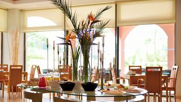 Un coin repas avec une table en verre, des chaises et un vase rempli de fleurs.