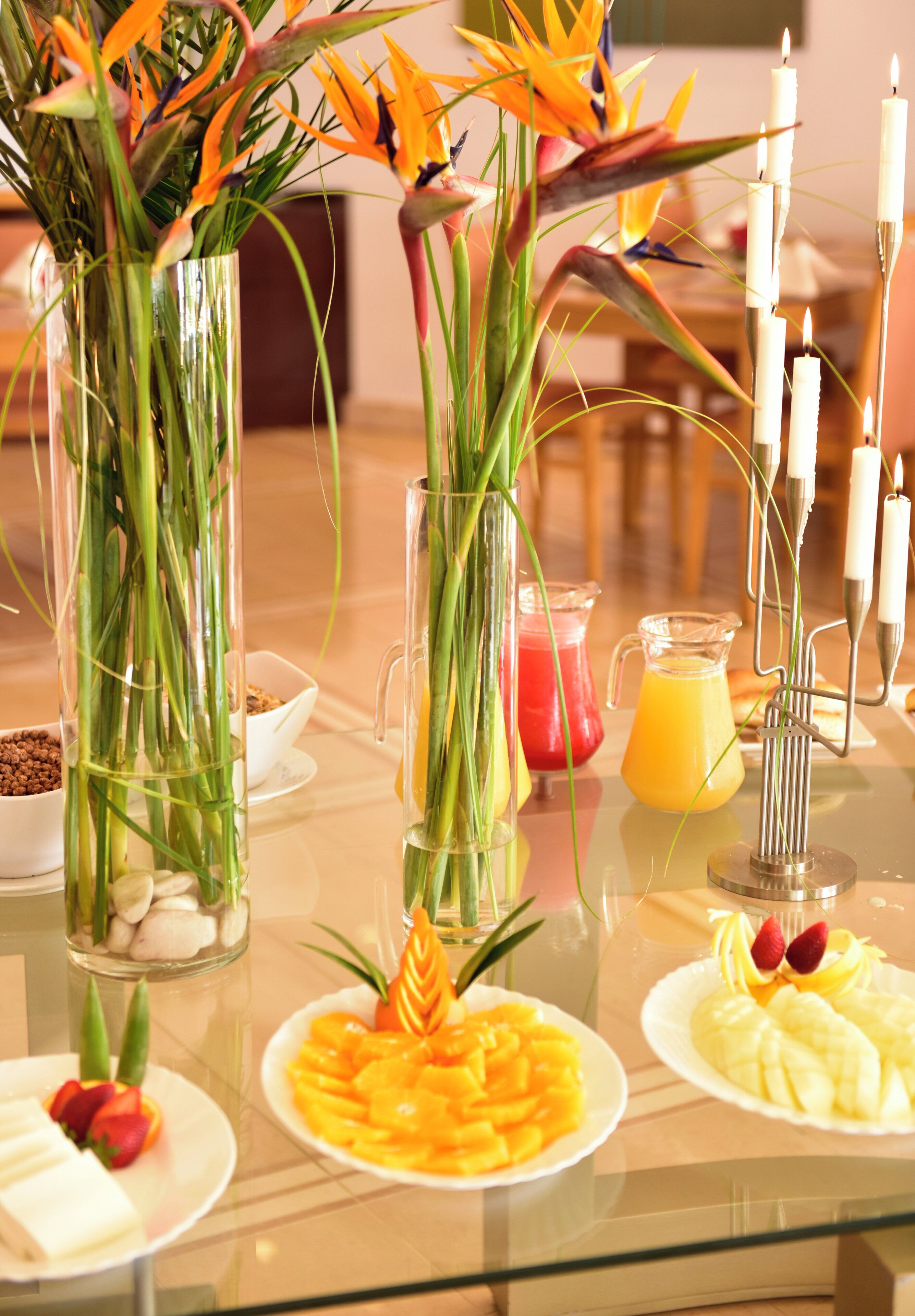 Una mesa con fruta, flores y velas.