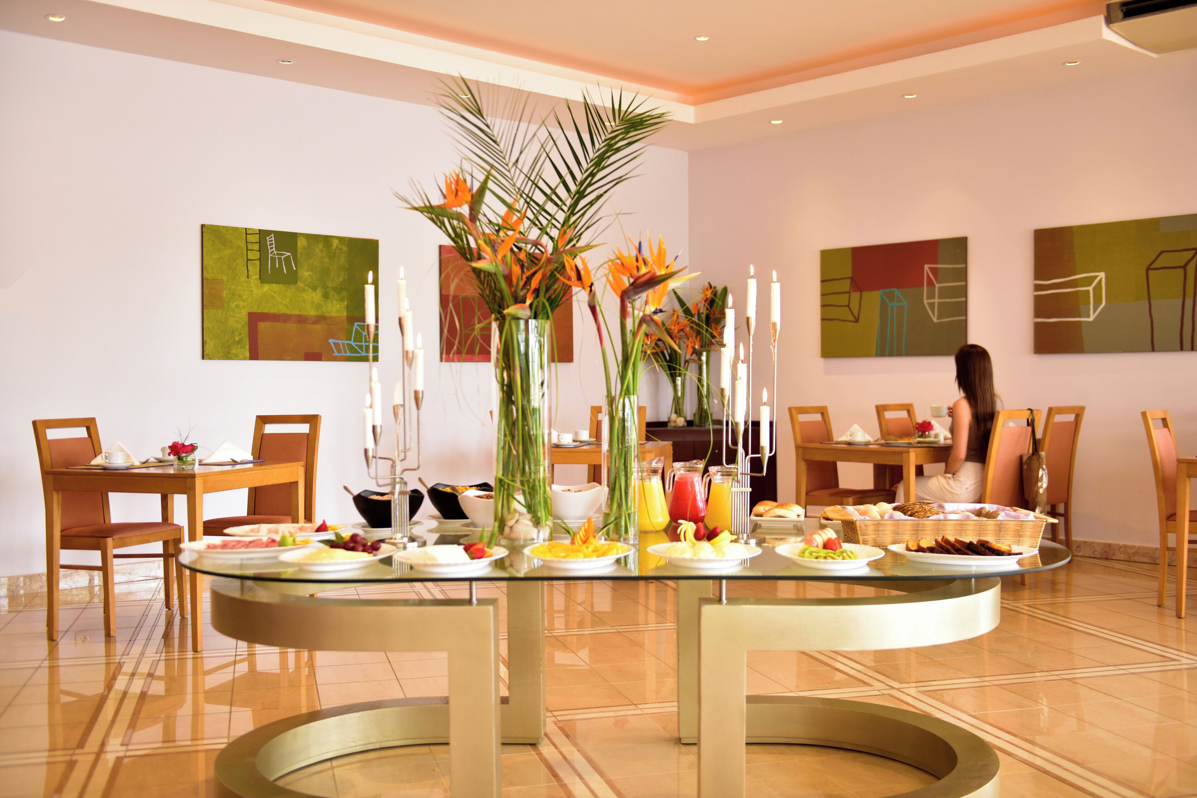 A dining area with a glass-top table, chairs, and various food items.