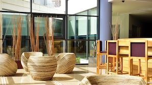 Ein modernes Interieur mit großen Glasfenstern, Rattanmöbeln und einem hölzernen Empfangstresen.