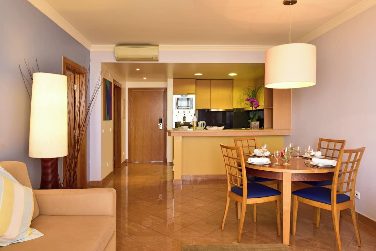 Hotelkamer met een zithoek, een bank, een lamp en een keuken op de achtergrond.