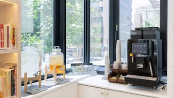 A coffee shop interior with a coffee machine, a large window, and bookshelves.
