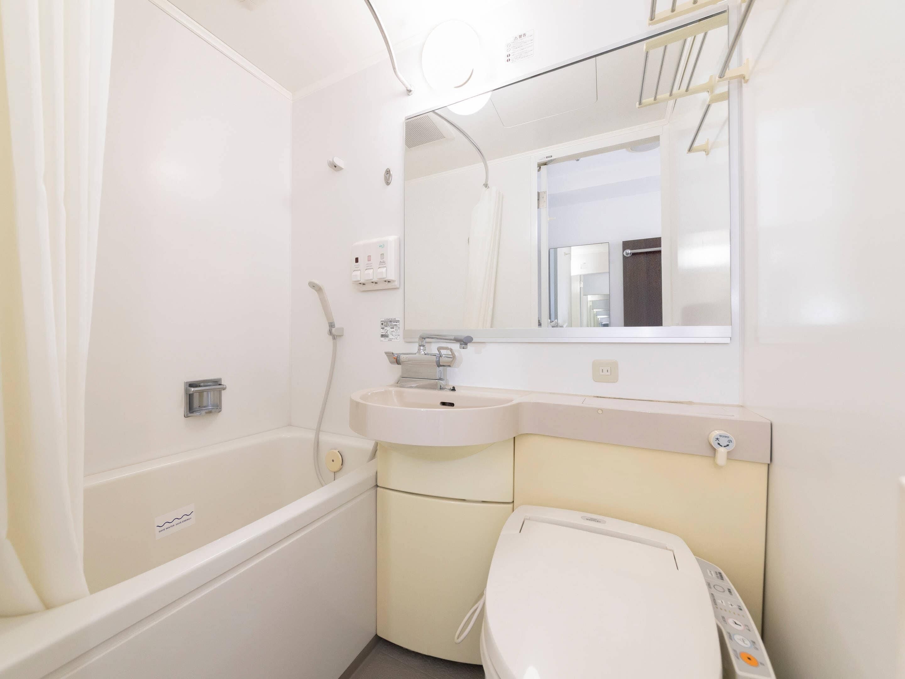 A bathroom with a bathtub, sink, mirror, and toilet.