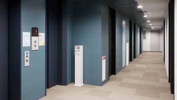 A hallway with a blue wall, an elevator, and a fire alarm.