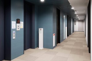 A hallway with a blue wall, an elevator, and a fire alarm. - Comfort Hotel Yokohama Kannai (Yokohama)