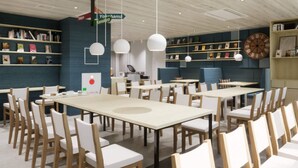 A modern dining area with multiple tables and chairs, a clock on the wall, and shelves with books and decorative items. - Comfort Hotel Yokohama Kannai (Yokohama)