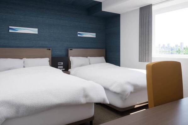 A hotel room with two beds, a wooden headboard, a desk, and a window with a city view. - Comfort Hotel Yokohama Kannai (Yokohama)