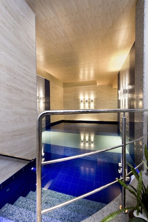 Una piscina cubierta, una piscina al aire libre, tumbonas