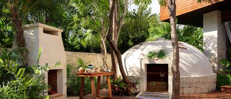 A wooden deck with a stone wall, a white dome structure, and lush greenery.