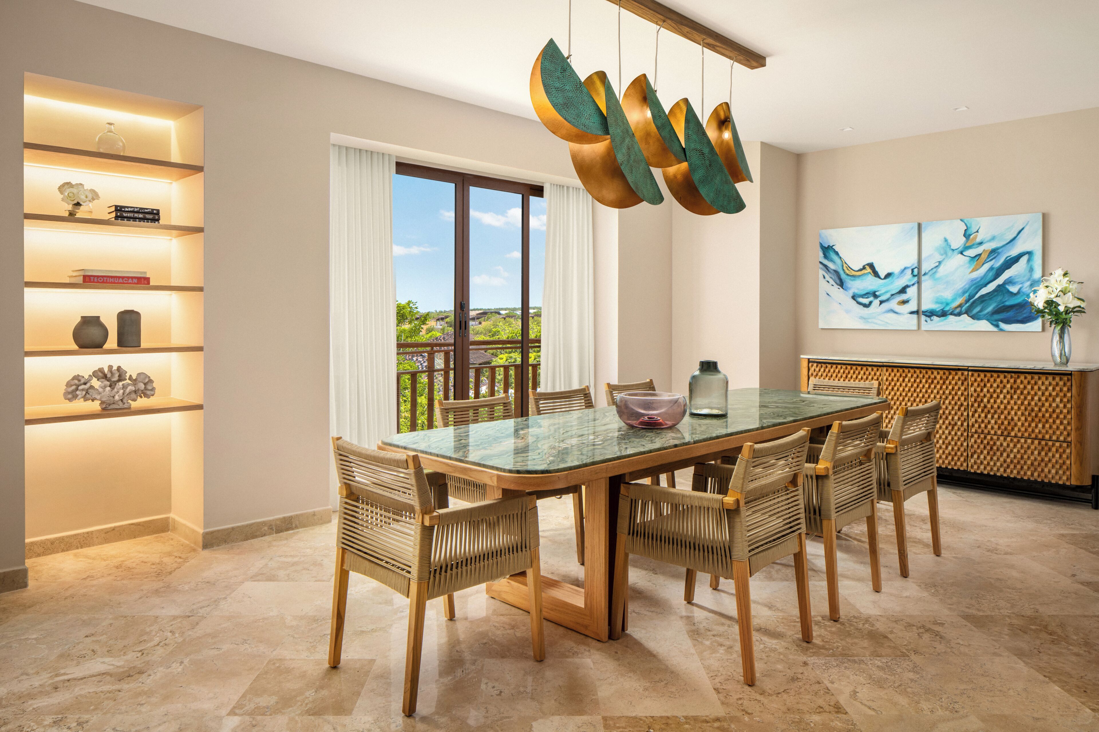 Un comedor con una mesa de vidrio, sillas de mimbre, una lámpara decorativa y vistas por un ventanal.