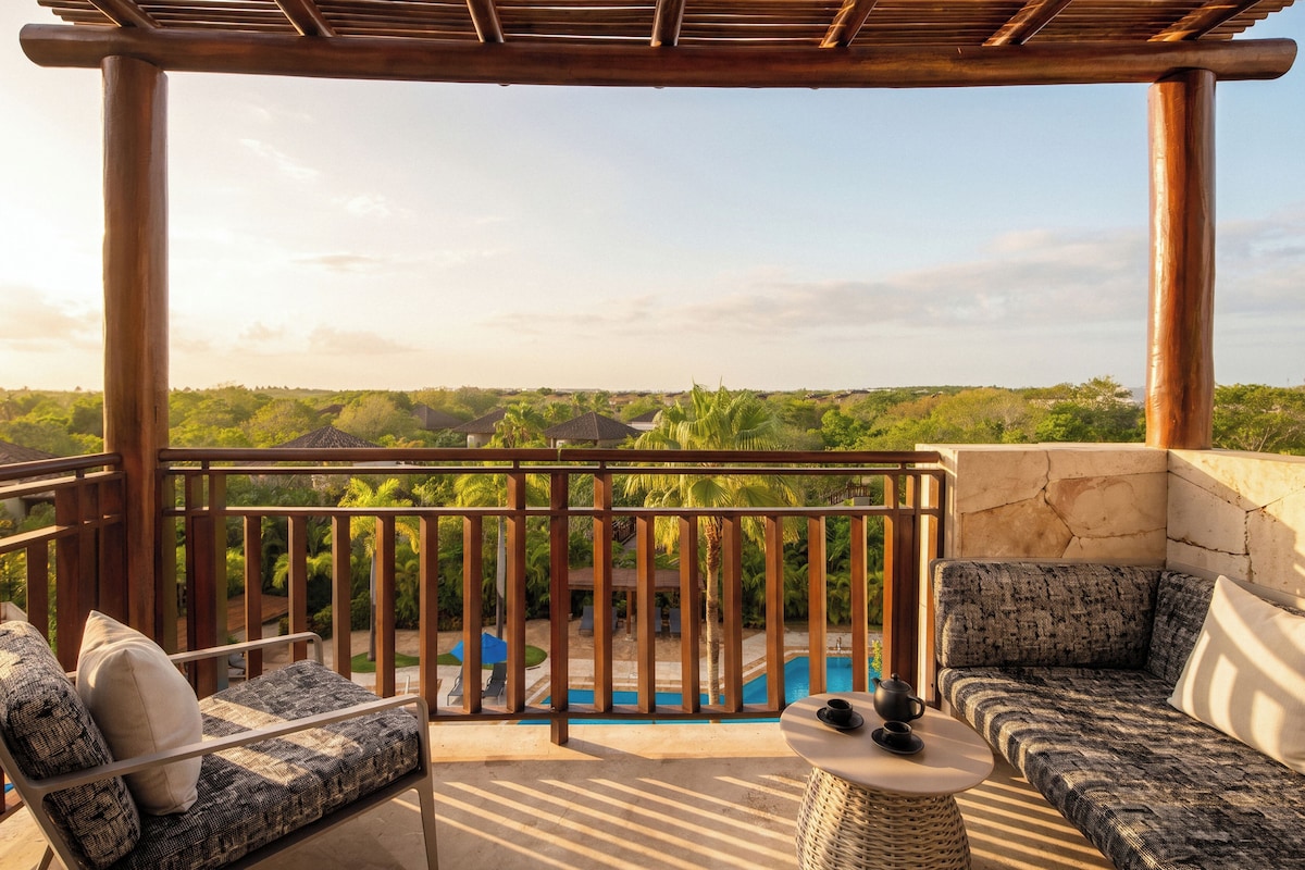 Un balcon avec vue sur une piscine et une végétation luxuriante.
