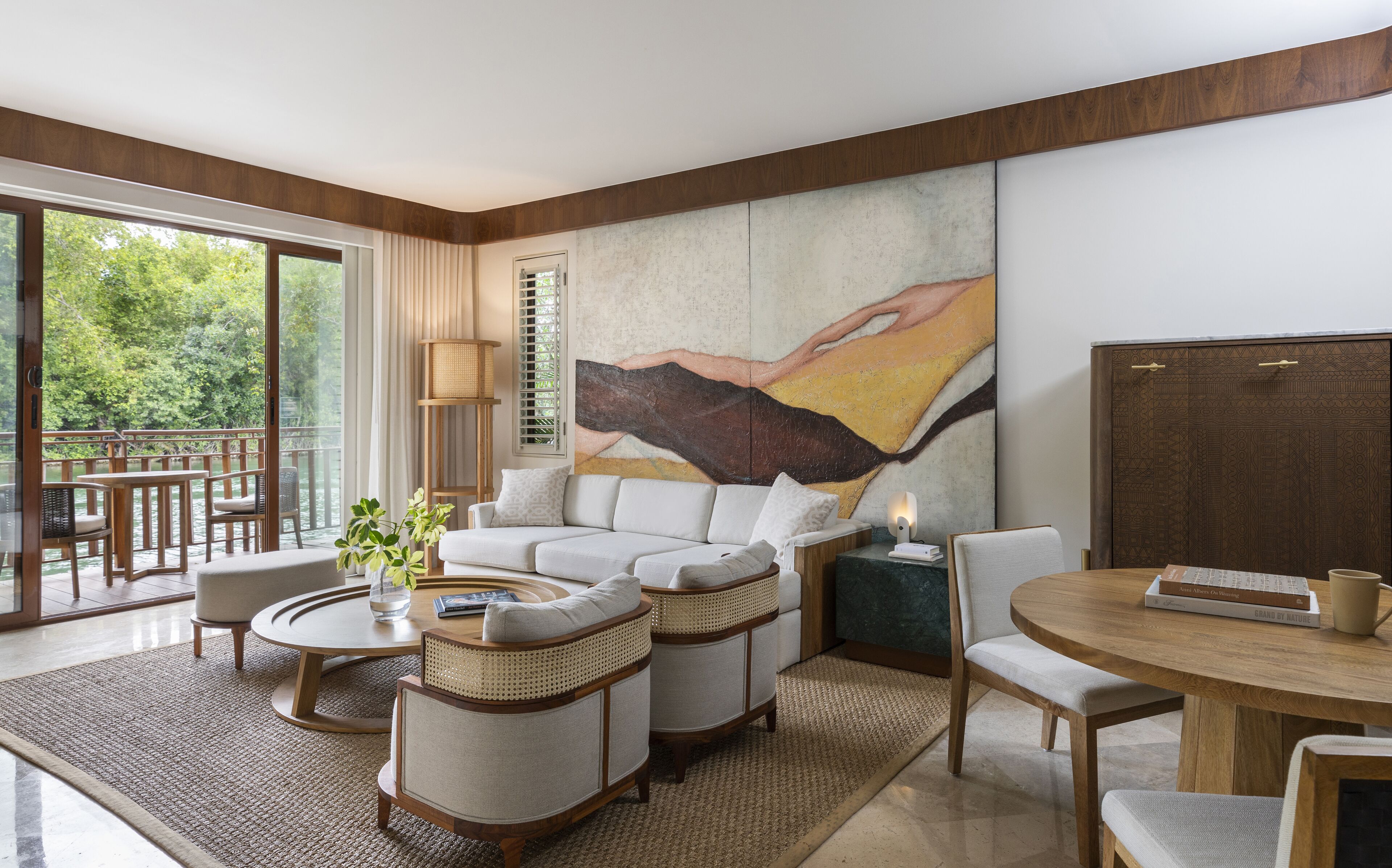 A modern living room with a large painting, a sofa, a coffee table, and a dining area with chairs.