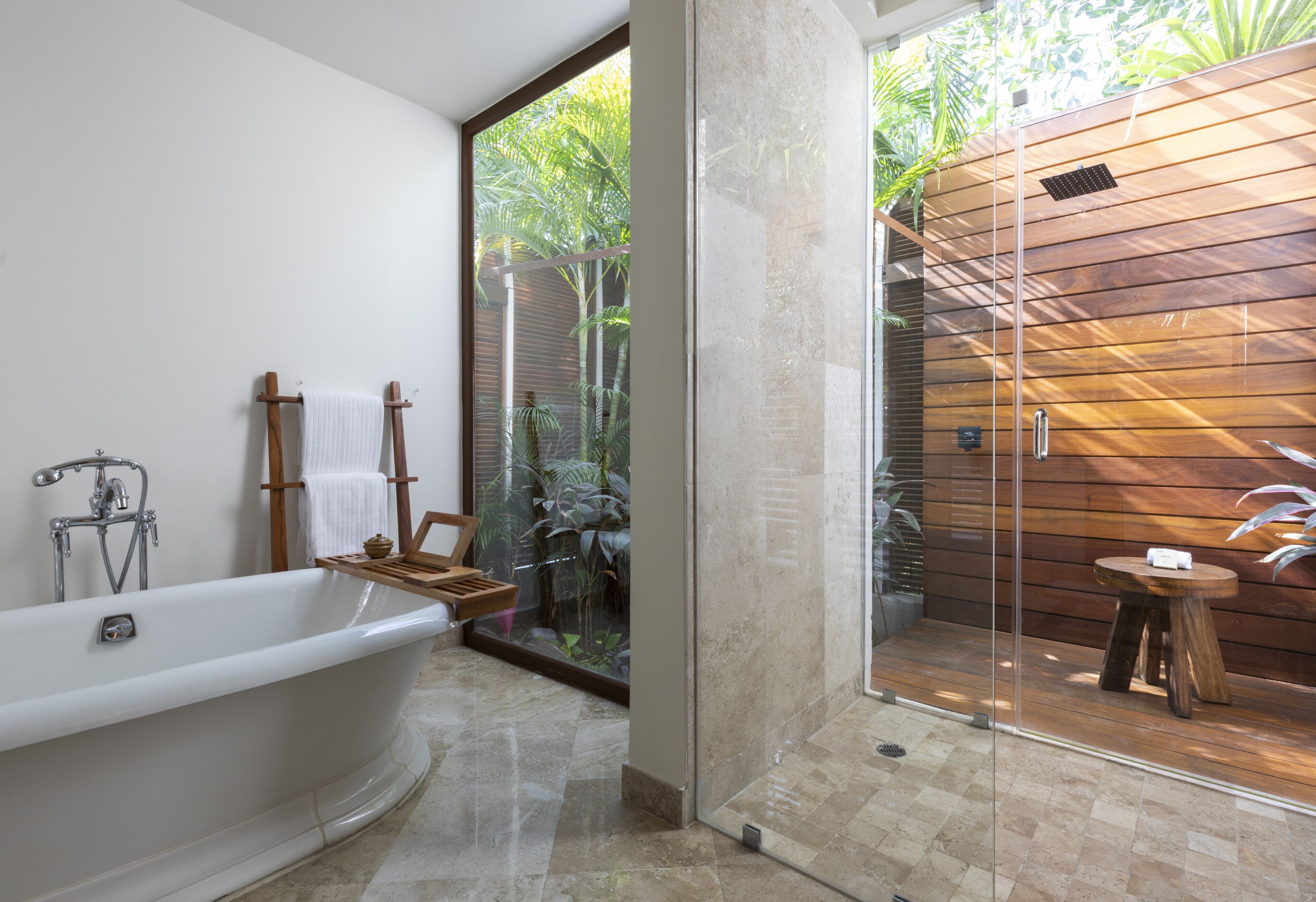 A modern bathroom with a freestanding bathtub, wooden towel rack, and a glass-enclosed shower area.