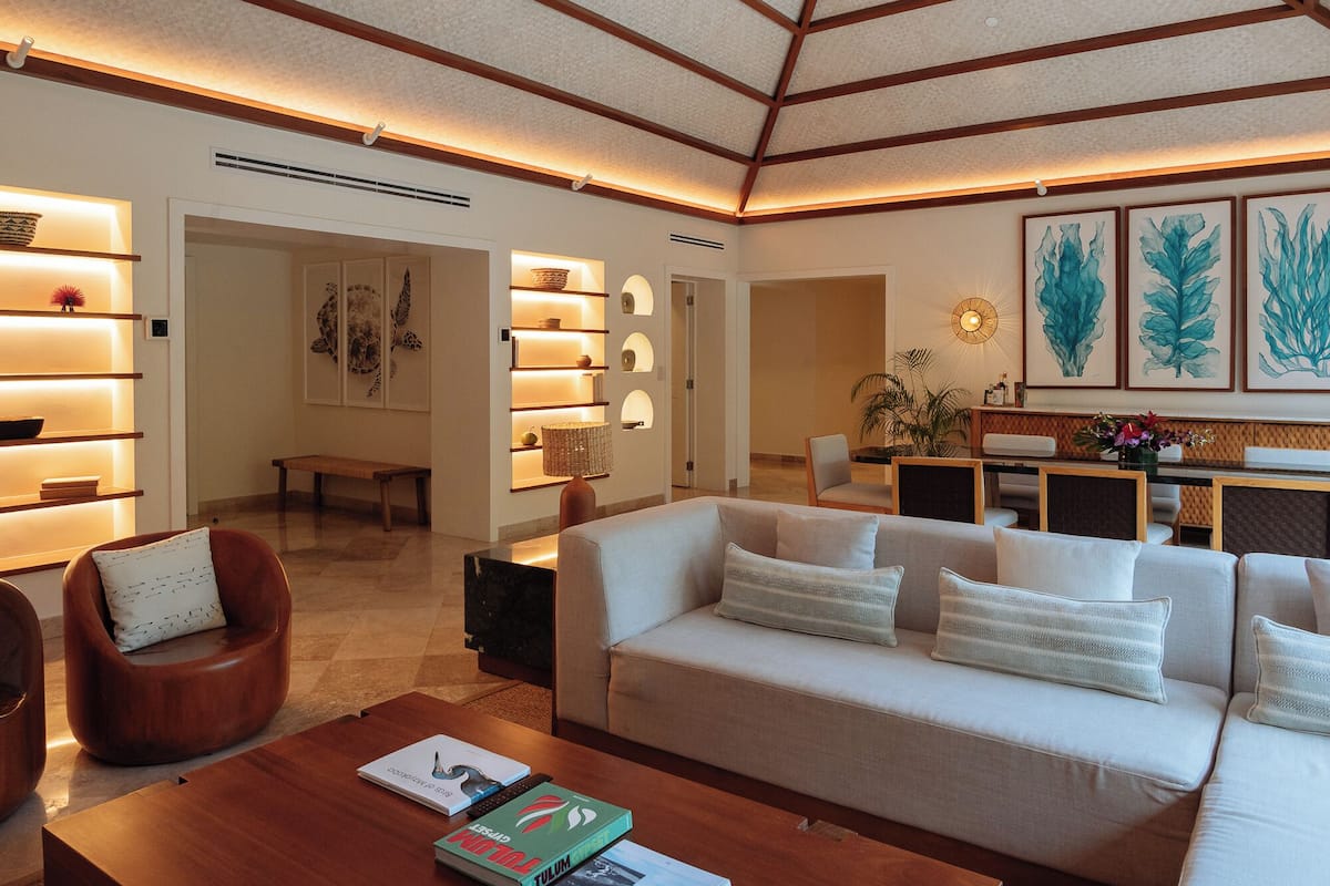 A modern living room with a sofa, armchairs, a coffee table, and a bookshelf.