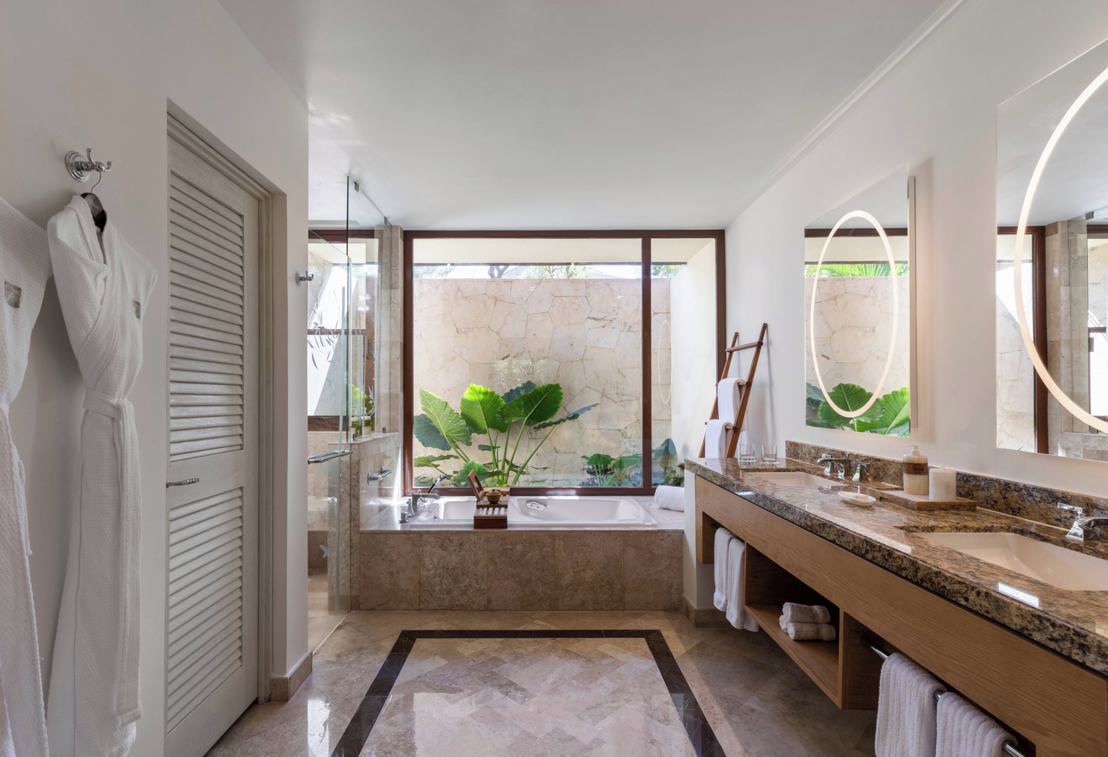 Un baño moderno con un ventanal grande, una bañera y un tocador con espejo.