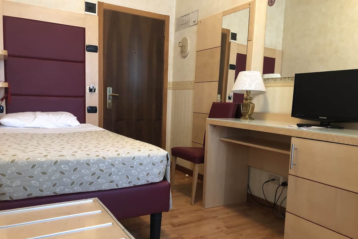 Une chambre d’hôtel comprenant un lit, un bureau, une chaise, une télévision et un miroir.