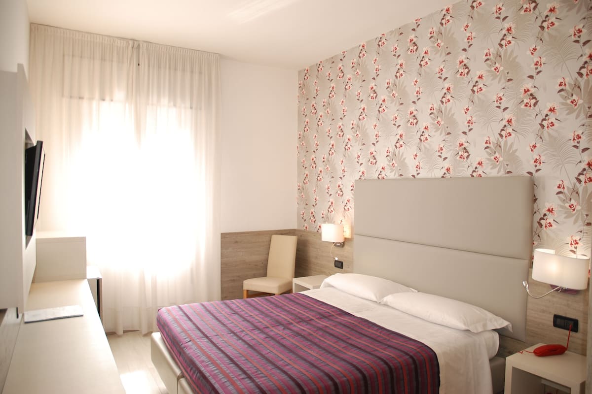 Une chambre d’hôtel avec un lit, une chaise, un bureau et un téléviseur.