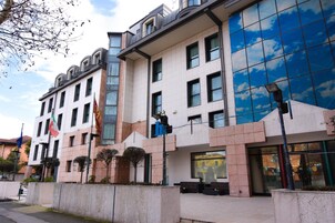 Un edificio moderno con facciata in vetro, numerose finestre e una bandiera.