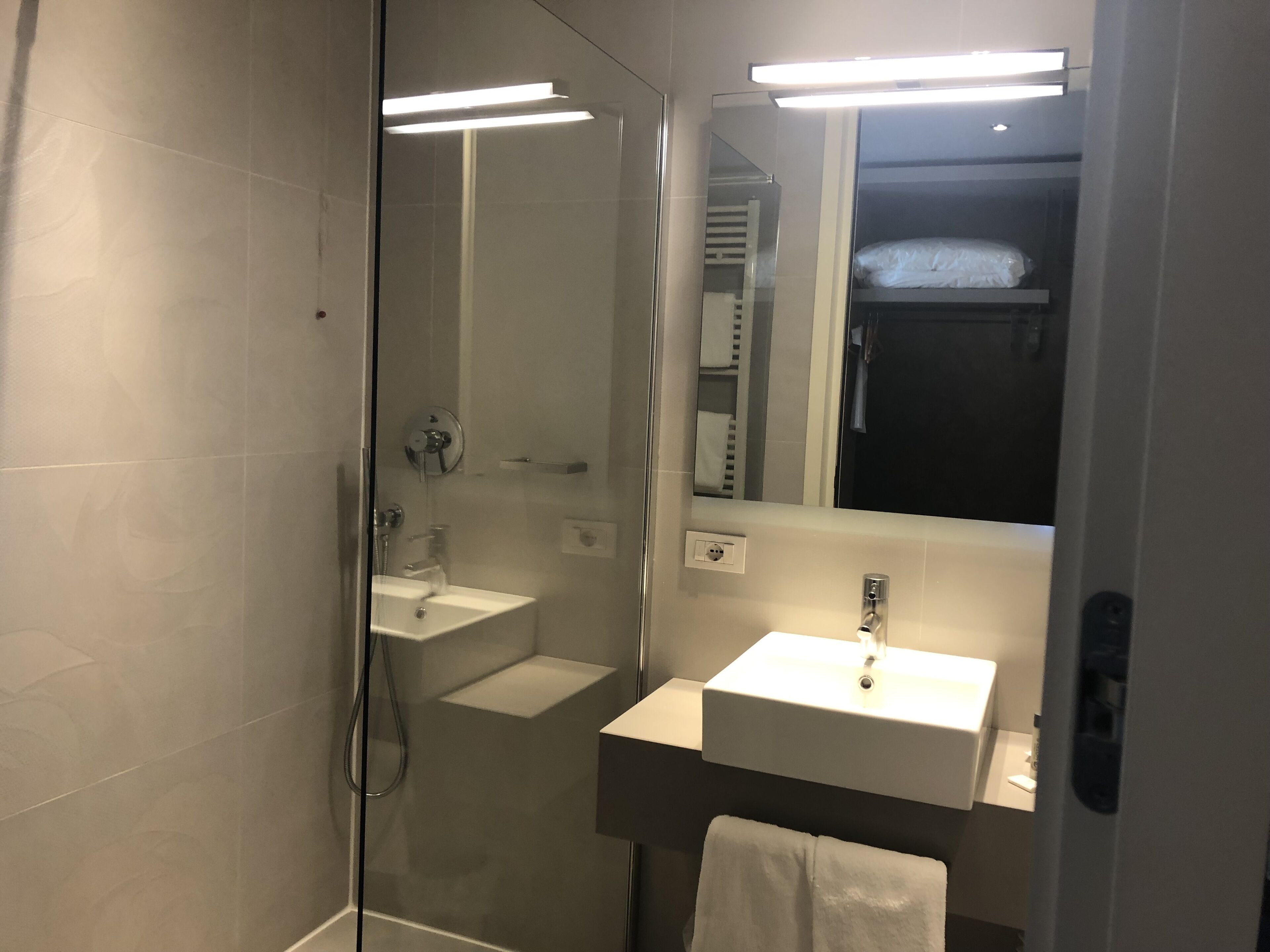 A modern bathroom with a glass shower enclosure, a white sink, and a mirror above the sink.