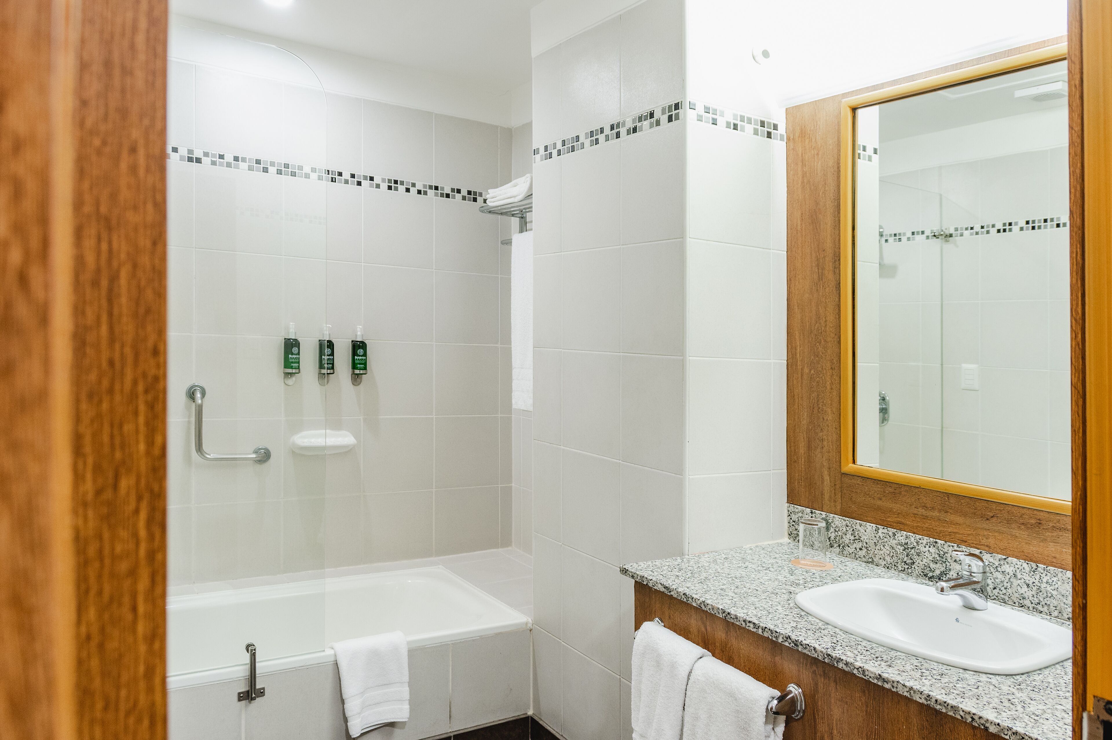 A bathroom with a shower, a sink, and a mirror.