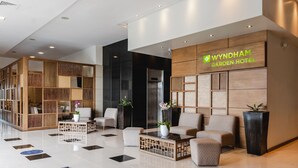 Un vestíbulo moderno con mostrador de recepción, zona de estar y un cartel del Hotel Wyndham Garden.