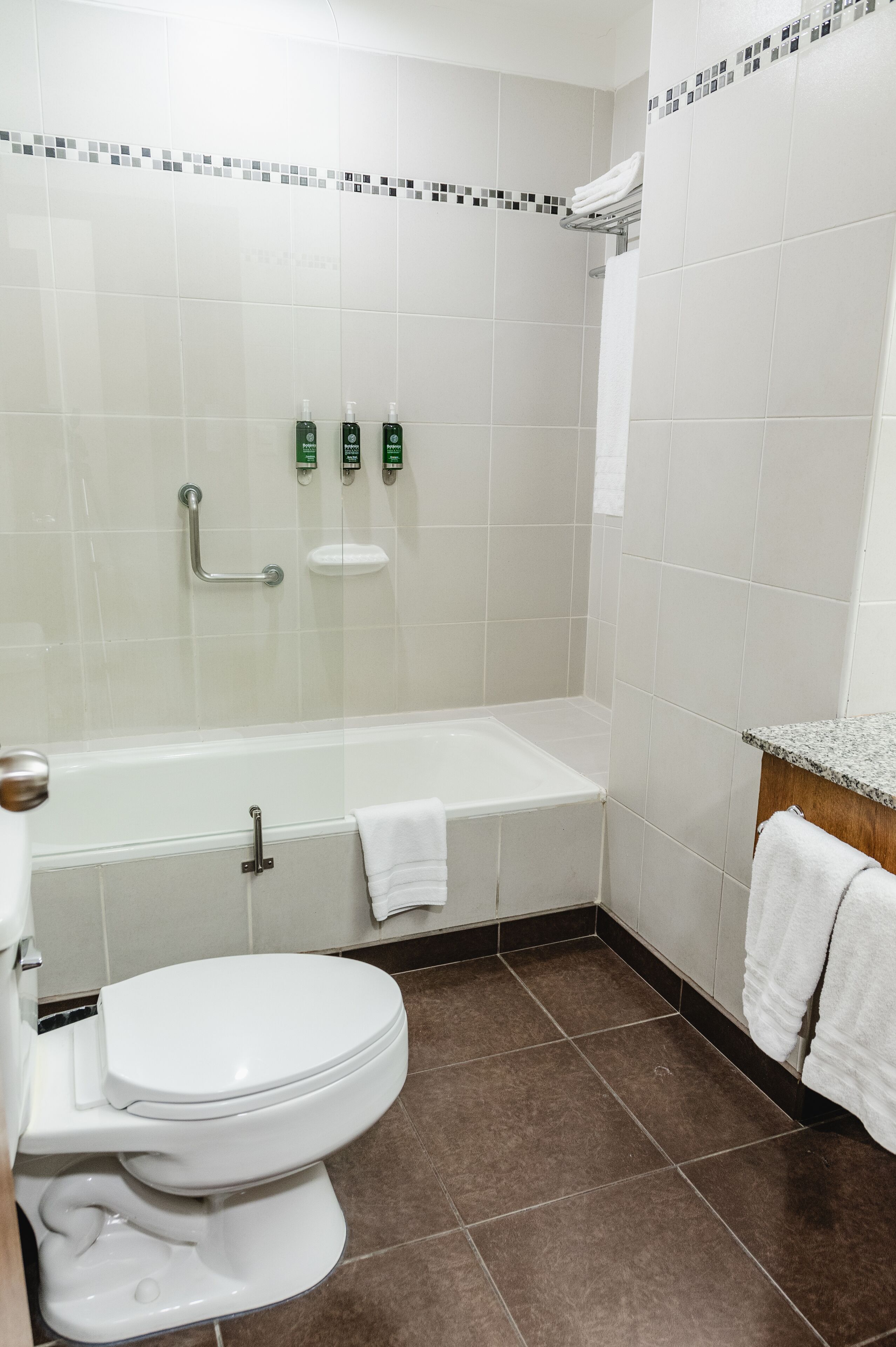 A bathroom with a white toilet, a bathtub, and a shower. There are two green bottles on the wall.