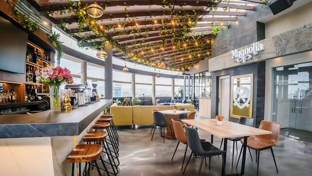 Zona moderna de bar con barra, taburetes y un área de estar con mesa y sillas.