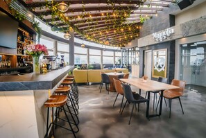 Zona moderna de bar con barra, taburetes y un área de estar con mesa y sillas.