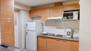 Una cocina moderna con armarios de madera, un refrigerador blanco, un microondas y una cafetera en la encimera.