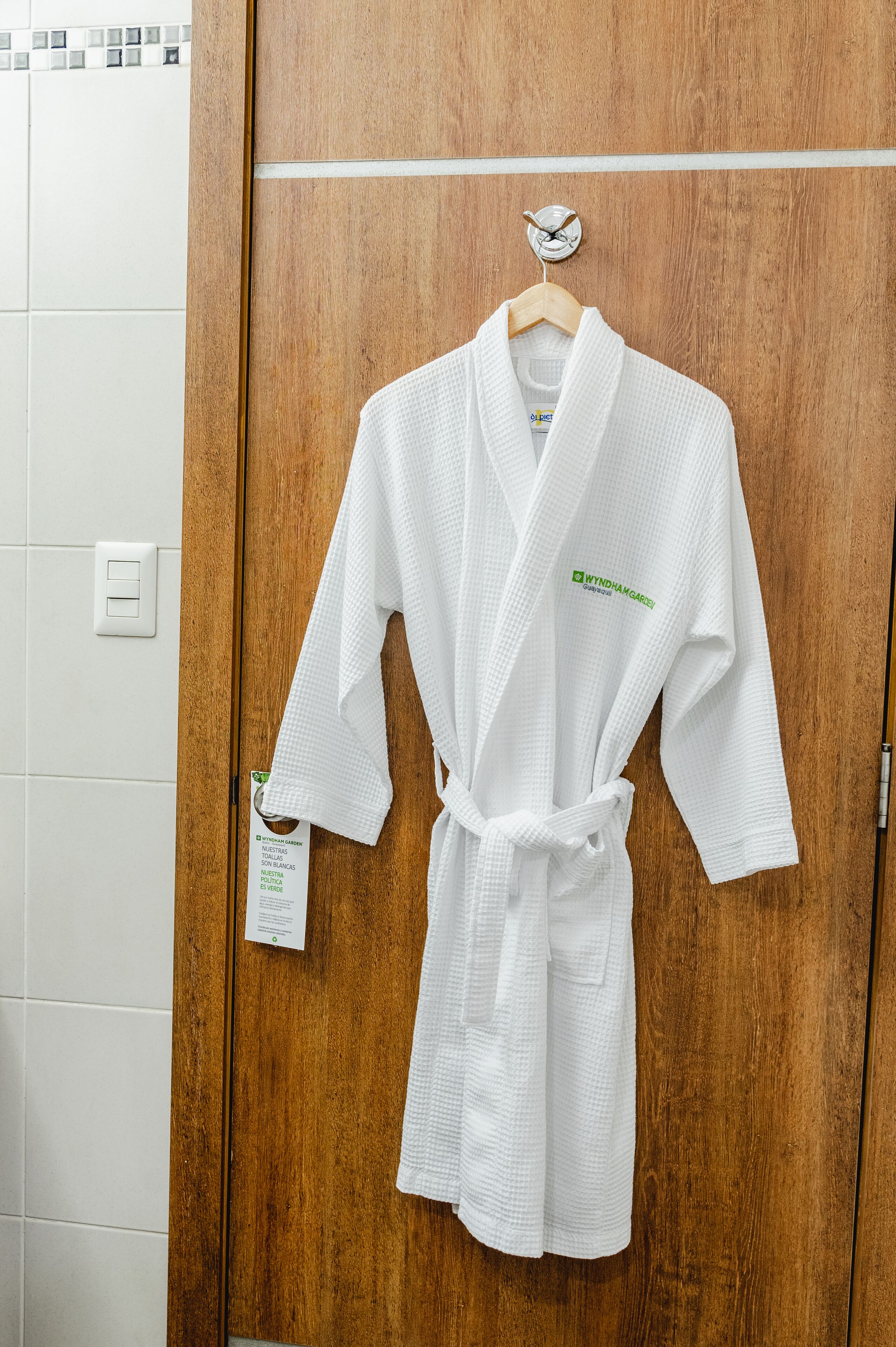 Un albornoz blanco colgado en una puerta de madera dentro de un baño.