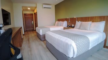 Habitación de hotel con dos camas, un escritorio, una silla y un equipo de aire acondicionado.