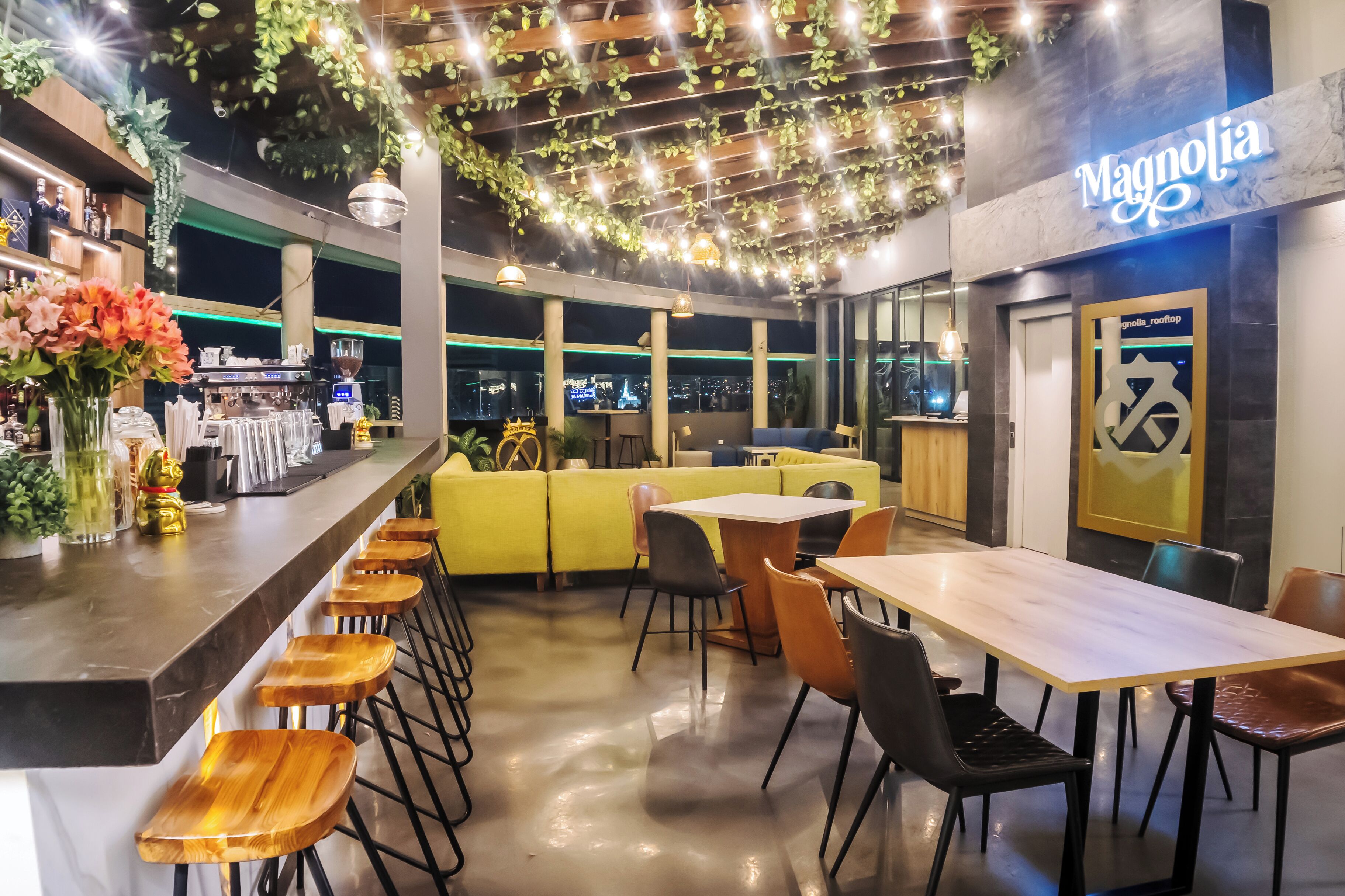 Un restaurante con zona de bar, asientos amarillos y vistas a la ciudad.