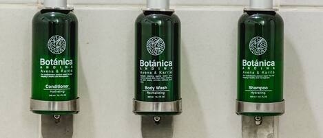 Three green bottles of Botanica products on a tiled wall.