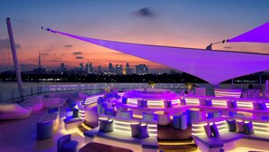A rooftop lounge with modern seating and a city skyline view at dusk. - Park Hyatt Dubai (Dubai)