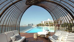 Un'area relax esterna di lusso con vista su una piscina e sullo skyline della città.