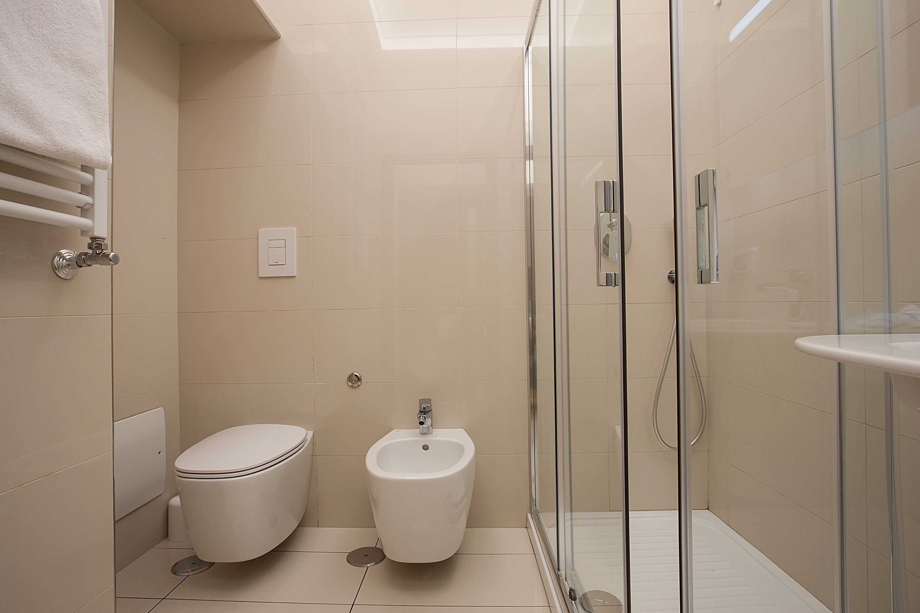 Uma casa de banho moderna com sanita, bidé e cabine de duche com vidro.