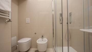 Een moderne badkamer met toilet, bidet en douchecabine.