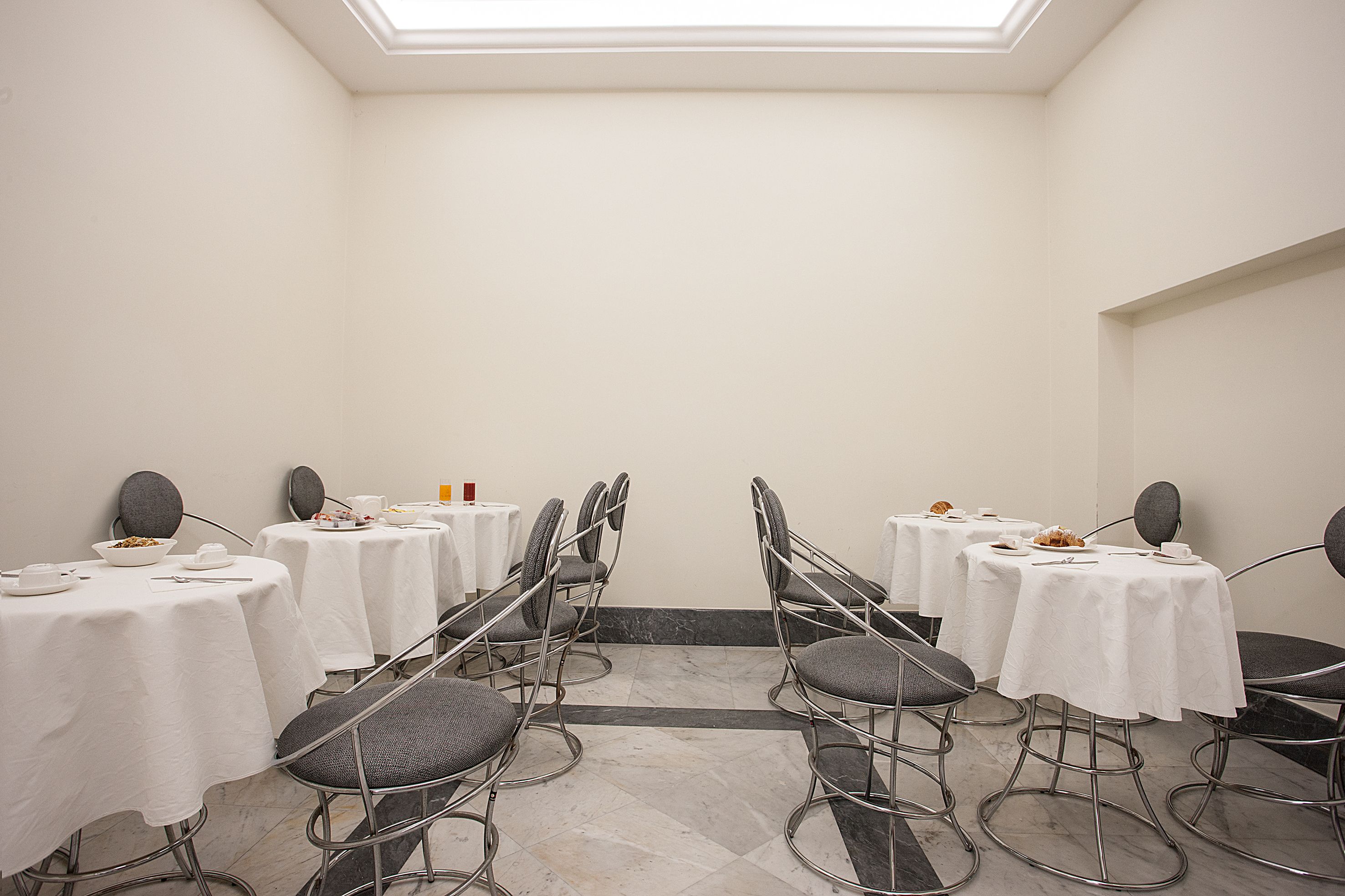 Une salle de conférence équipée de tables rondes, de chaises et d’une verrière.
