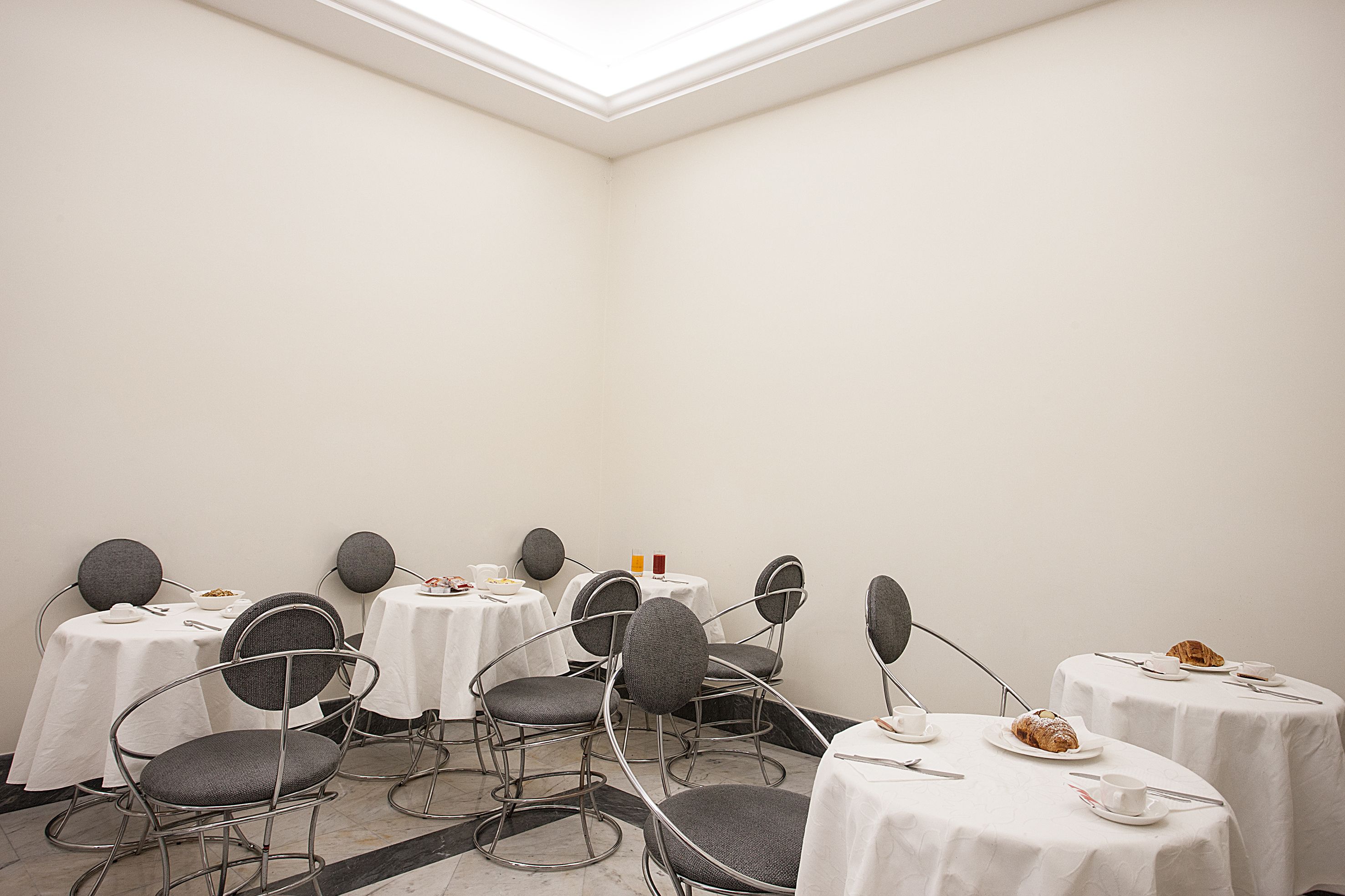 A conference room with round tables, grey chairs, and white tablecloths.
