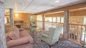 A log cabin interior with a wooden floor, a sofa, two armchairs, a glass coffee table, and a stone wall. - Lake Chatuge Lodge (Hiawassee)