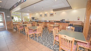 A restaurant with multiple tables and chairs, a counter with a coffee machine, and a fire extinguisher on the wall. - Lake Chatuge Lodge (Hiawassee)