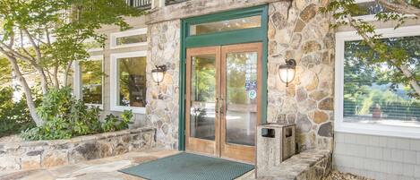 A stone building with a green door, a stone staircase, and a stone patio.