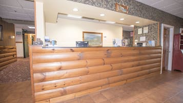 A reception desk with a wooden panel design, a framed picture on the wall, and a tiled floor.