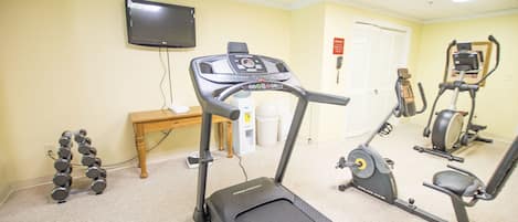 A fitness room with treadmills, a stationary bike, and dumbbells.