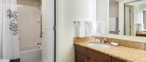 Baño con ducha, inodoro, lavabo y espejo.