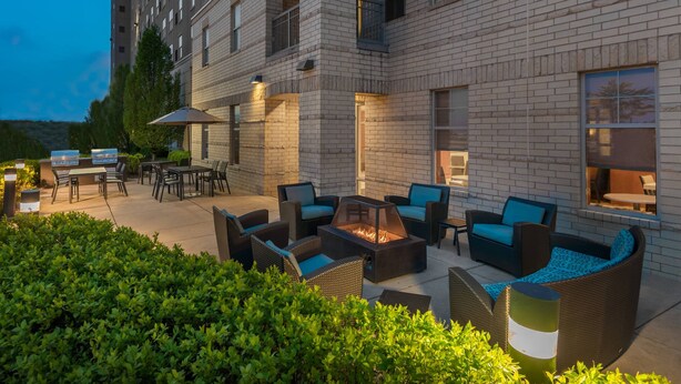 Een terras buiten met zitplaatsen, een vuurkorf en een barbecue.