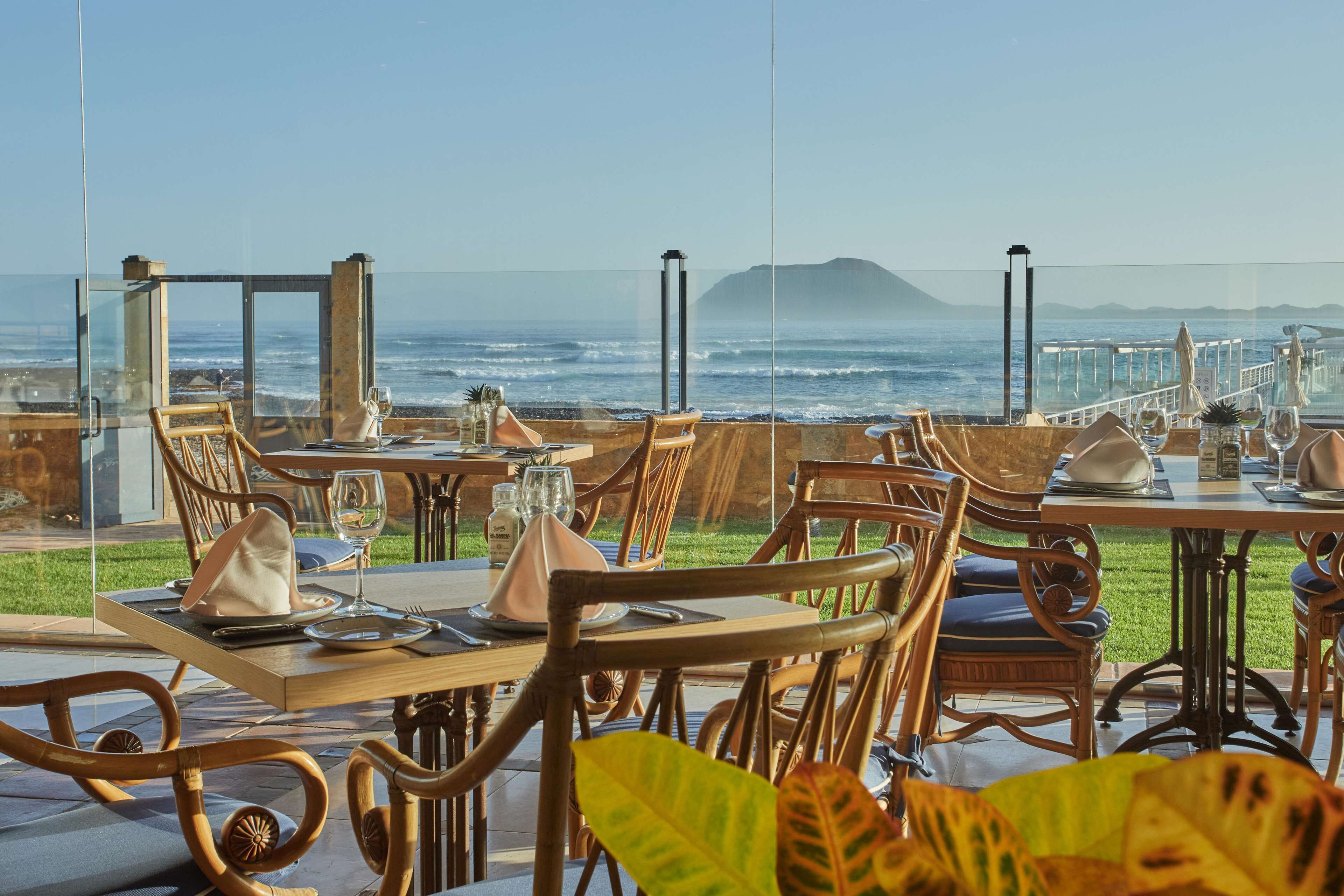 An outdoor dining area with tables and chairs, overlooking the ocean.