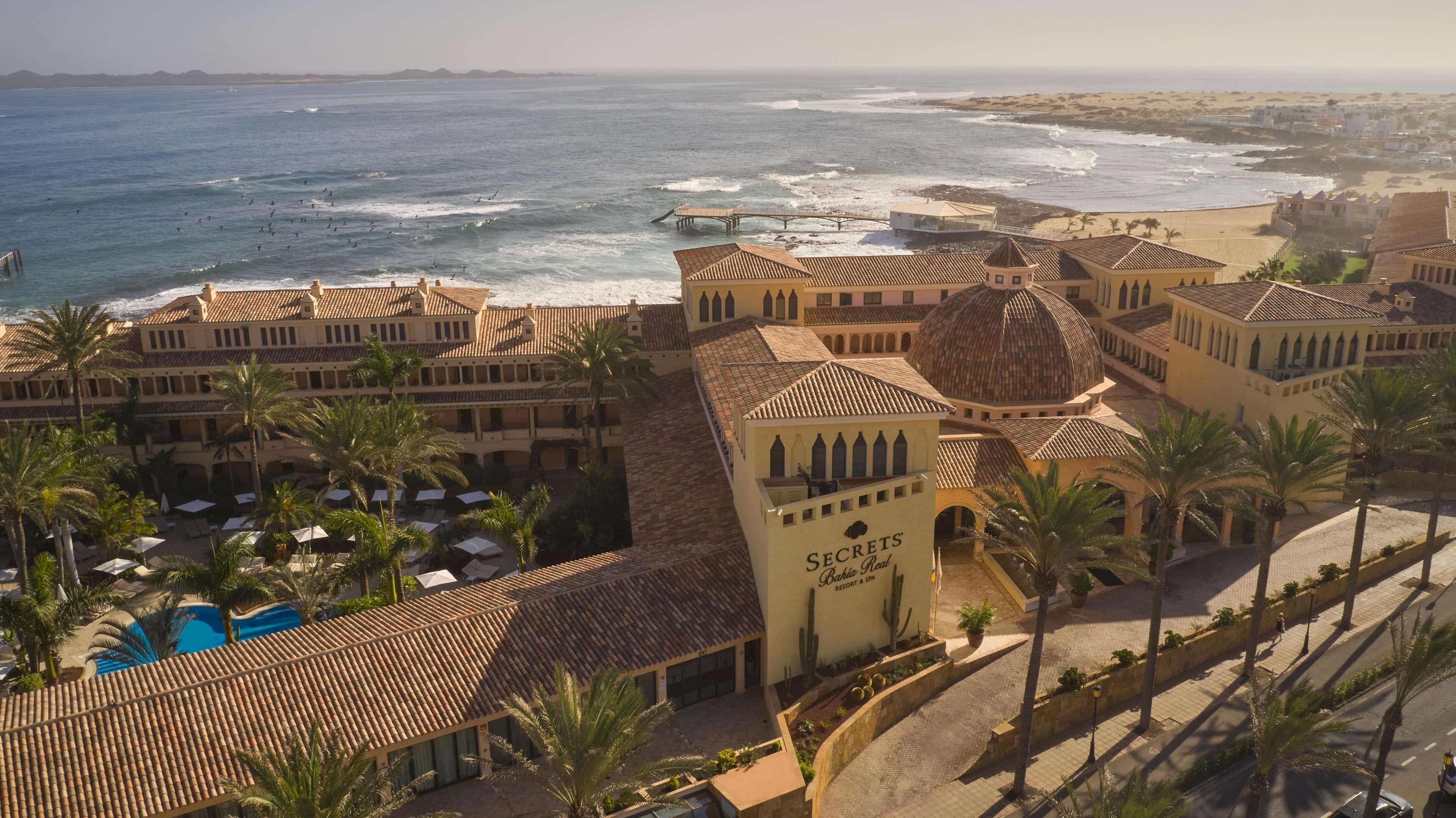 A resort with a pool, palm trees, and a beach view.
