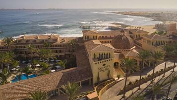 A resort with a pool, palm trees, and a beach view.